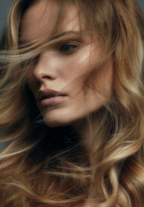 Side profile of a woman with wavy blonde and brown hair, showing a bouncy, voluminous finish