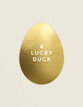 Gold egg-shaped object with 'A LUCKY DUCK' text on a beige background