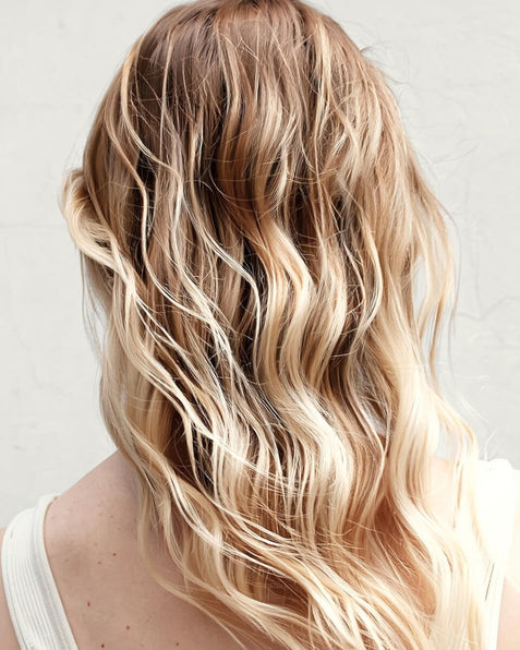Blonde hair with wavy texture blow dry on a plain background