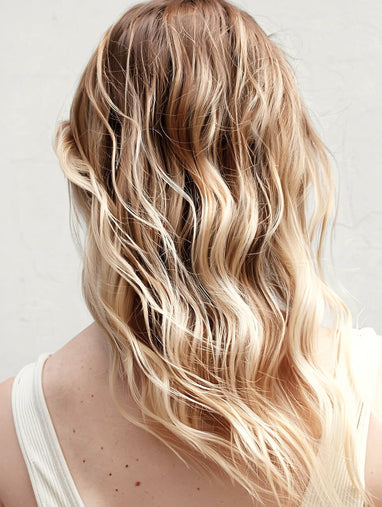 Blonde hair with wavy texture blow dry on a plain background
