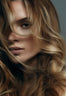 Close-up of a woman with long wavy hair in blended blonde and brown tones, styled after a blow dry