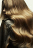 Back view of a woman with long wavy hair in blended blonde and brown tones
