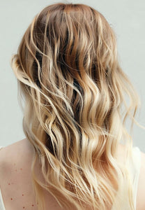 Close-up back view of a woman with long curly blonde hair
