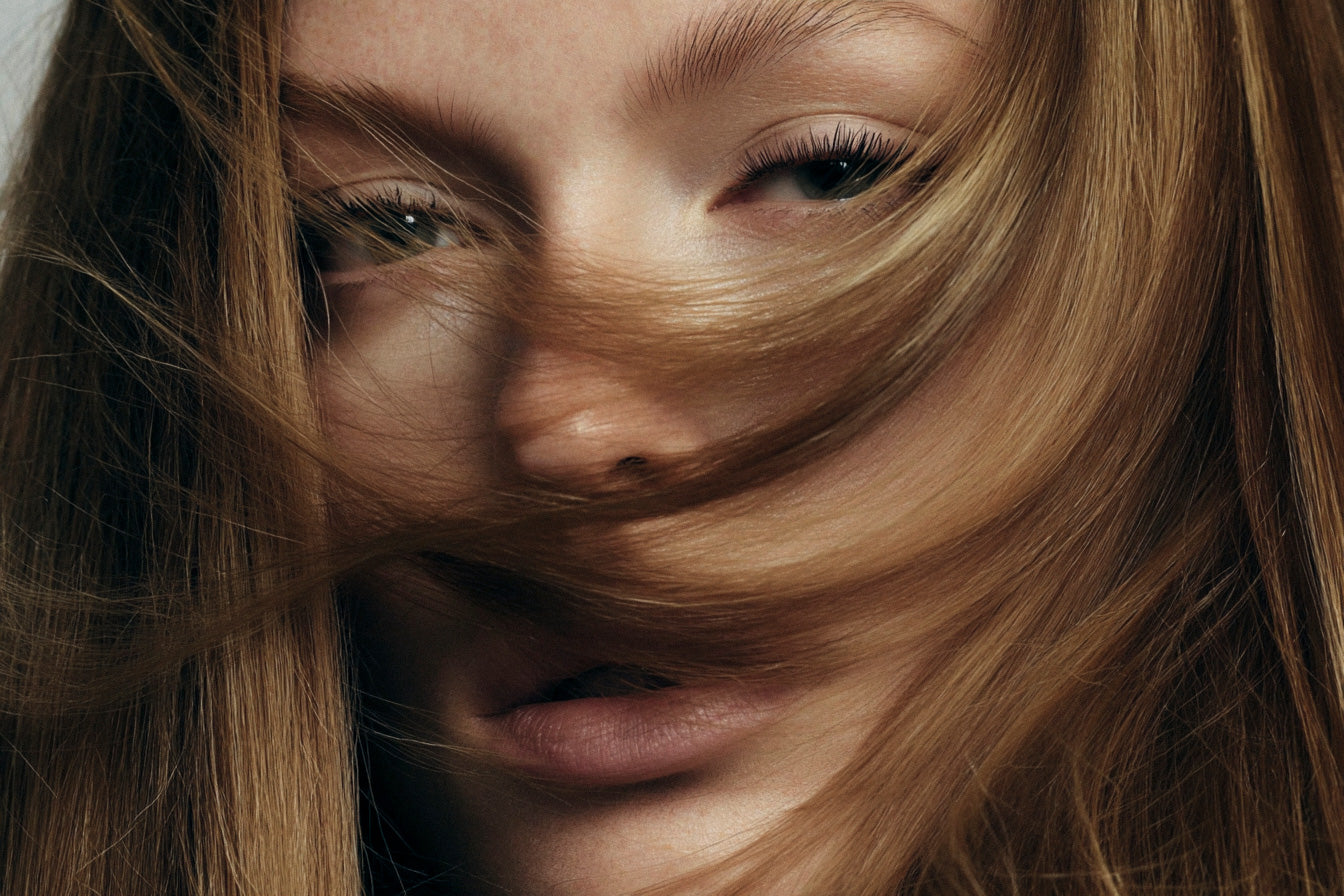 Close-up of a person with long, wavy hair covering part of their face.