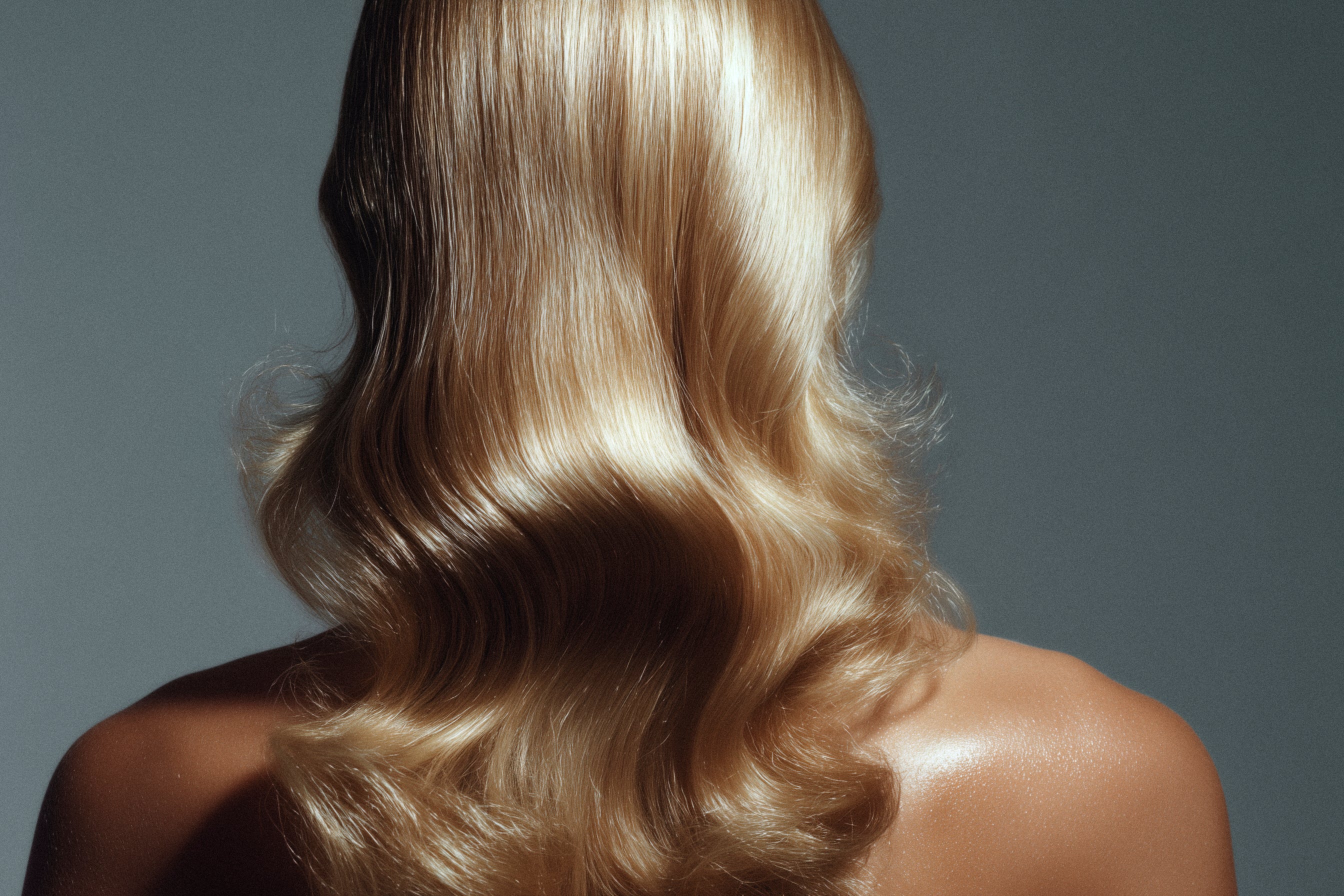 Blonde hair styled in loose waves on a gray background