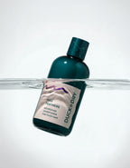 Duck & Dry conditioner bottle with label partially submerged in water on a white background