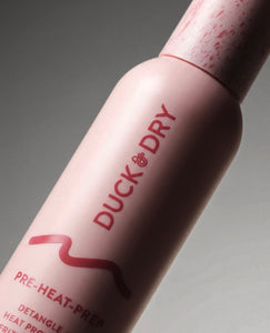 Pink hair product bottle with 'Duck & Dry' branding on a gray background