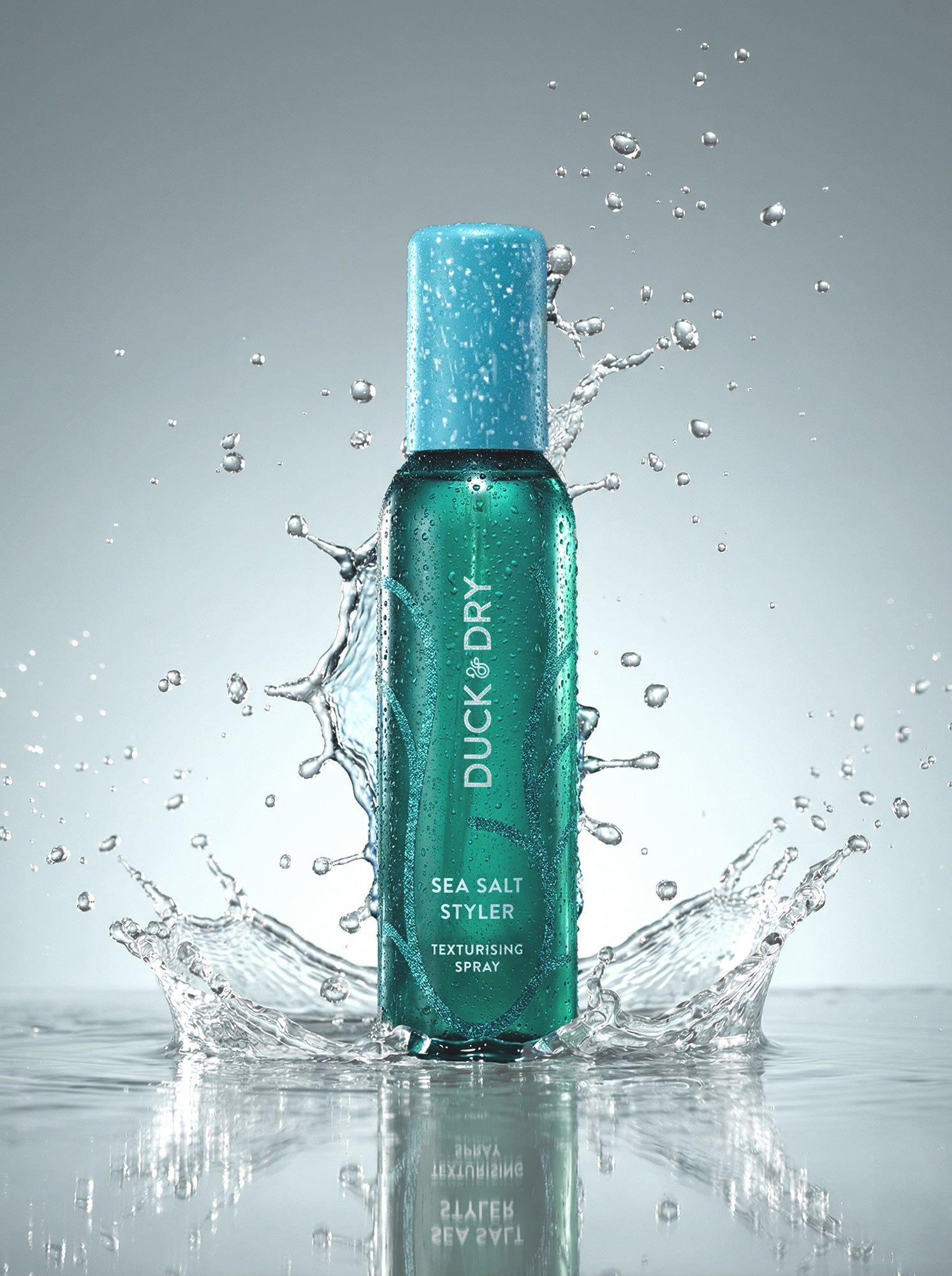 Duck & Dry Sea Salt Styler spray bottle with water splashes on a gray background