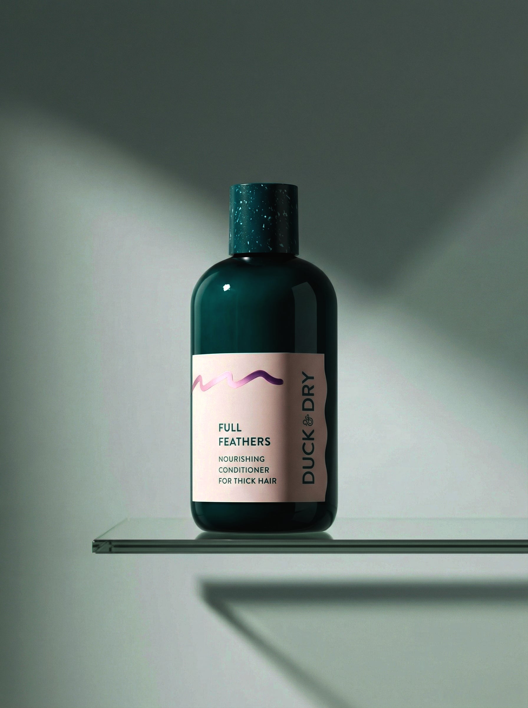 Bottle of Duck & Dry Full Feathers conditioner on a glass shelf with a gray background