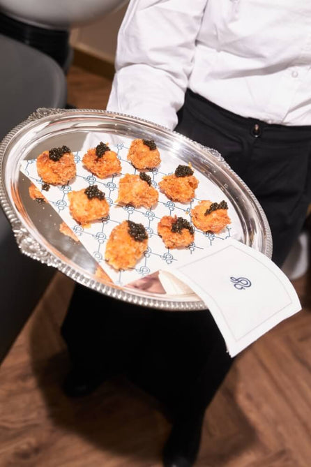 Waiter carrying a silver tray of caviar-topped canapés at a Duck & Dry salon event