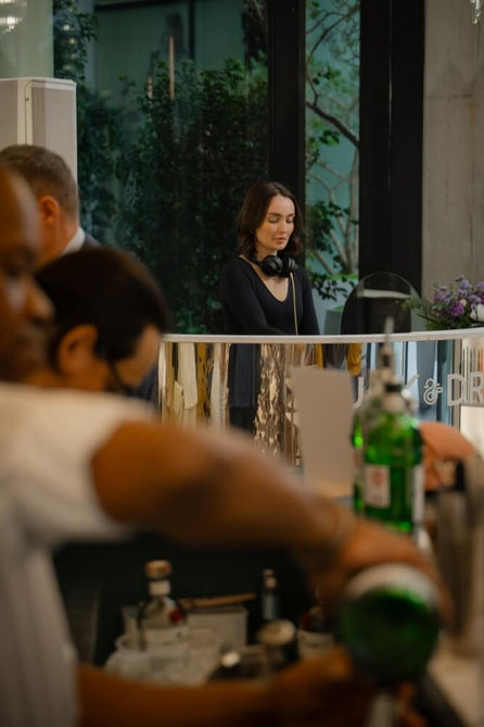 DJ playing at a Duck & Dry salon event, with a bartender mixing drinks in the foreground